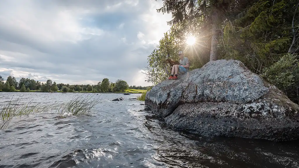 barn sitter på sten vid sjö