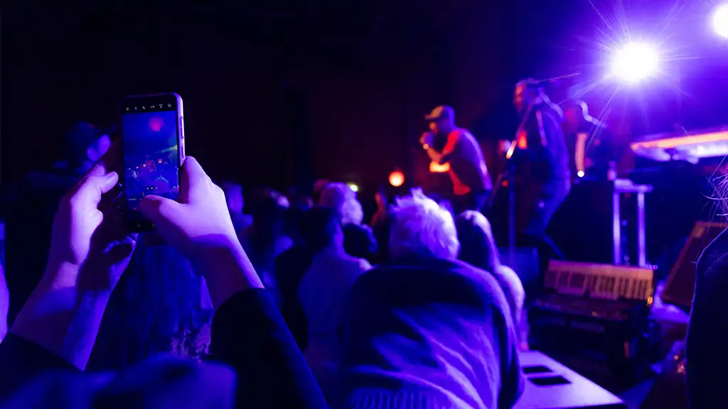 livekonsert och någon som tar en bild med sin mobil