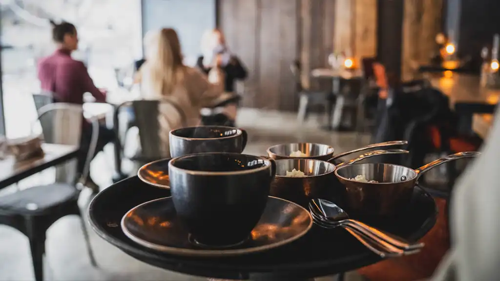 restaurangmiljö med koppar och bestick i förgrunden